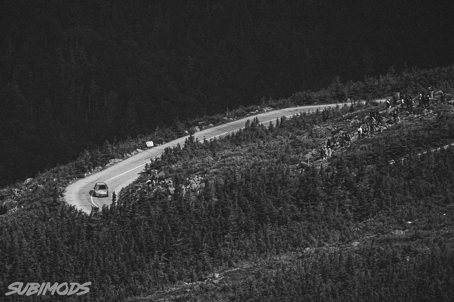 The Evolution on a switchback with spectators lining the mountain road